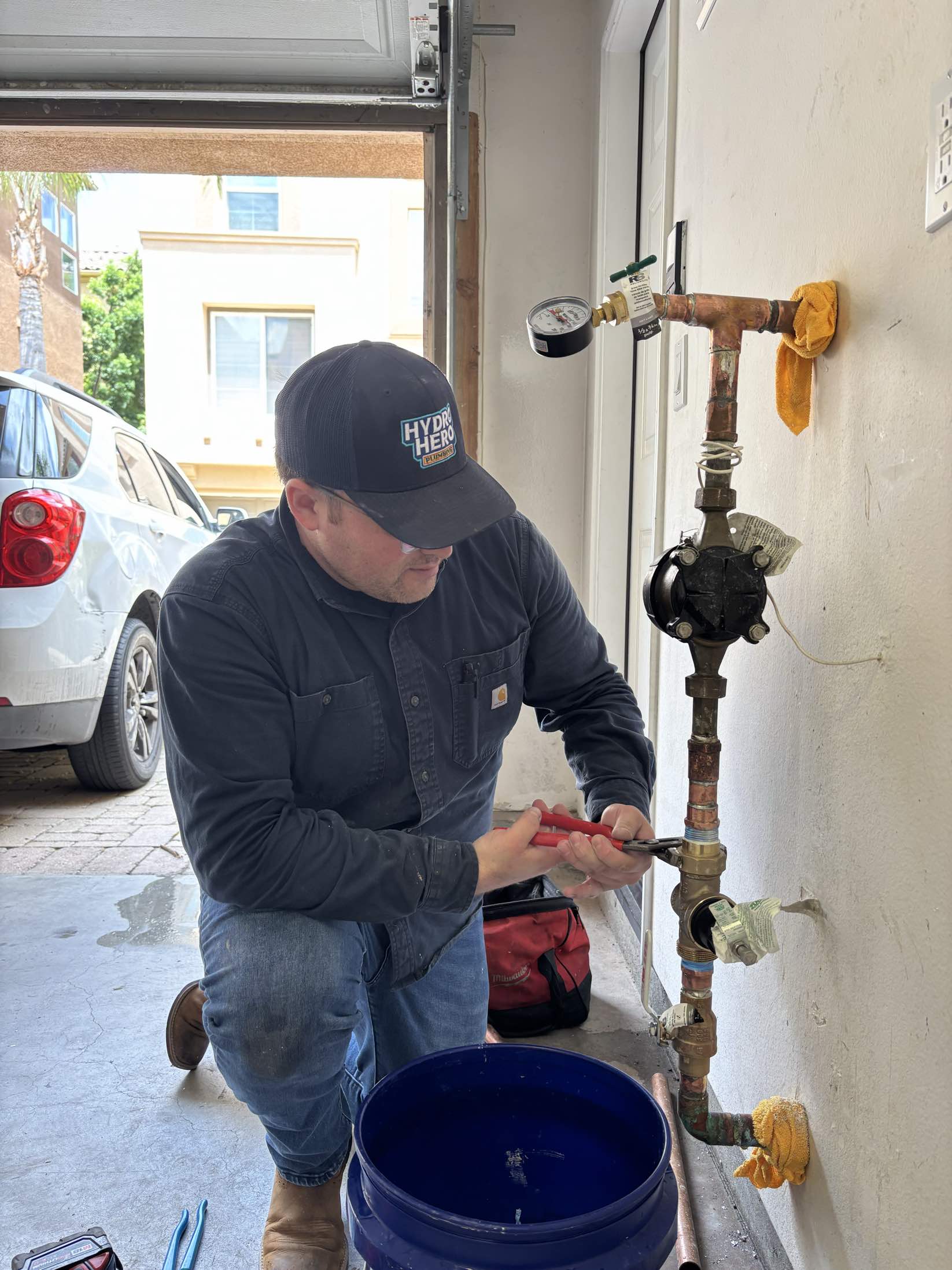 Hydro Hero plumber servicing a copper water line and pressure gauge in a Chula Vista garage